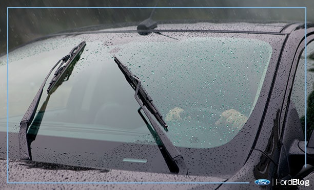 Limpiaparabrisas quitan la lluvia de los vidrios de un auto Ford