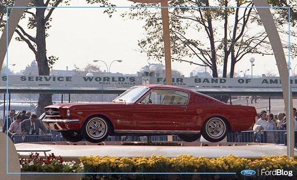 Ford Mustang 1964 rojo en una exhibicion frente a multitud
